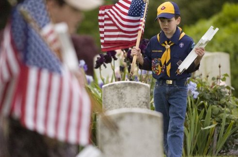 Cub Scout Eli Pugsley, 7, carries flags and crosses to decorate the graves of veterans in Mother Joseph Catholic Cemetery in Vancouver on Saturday.